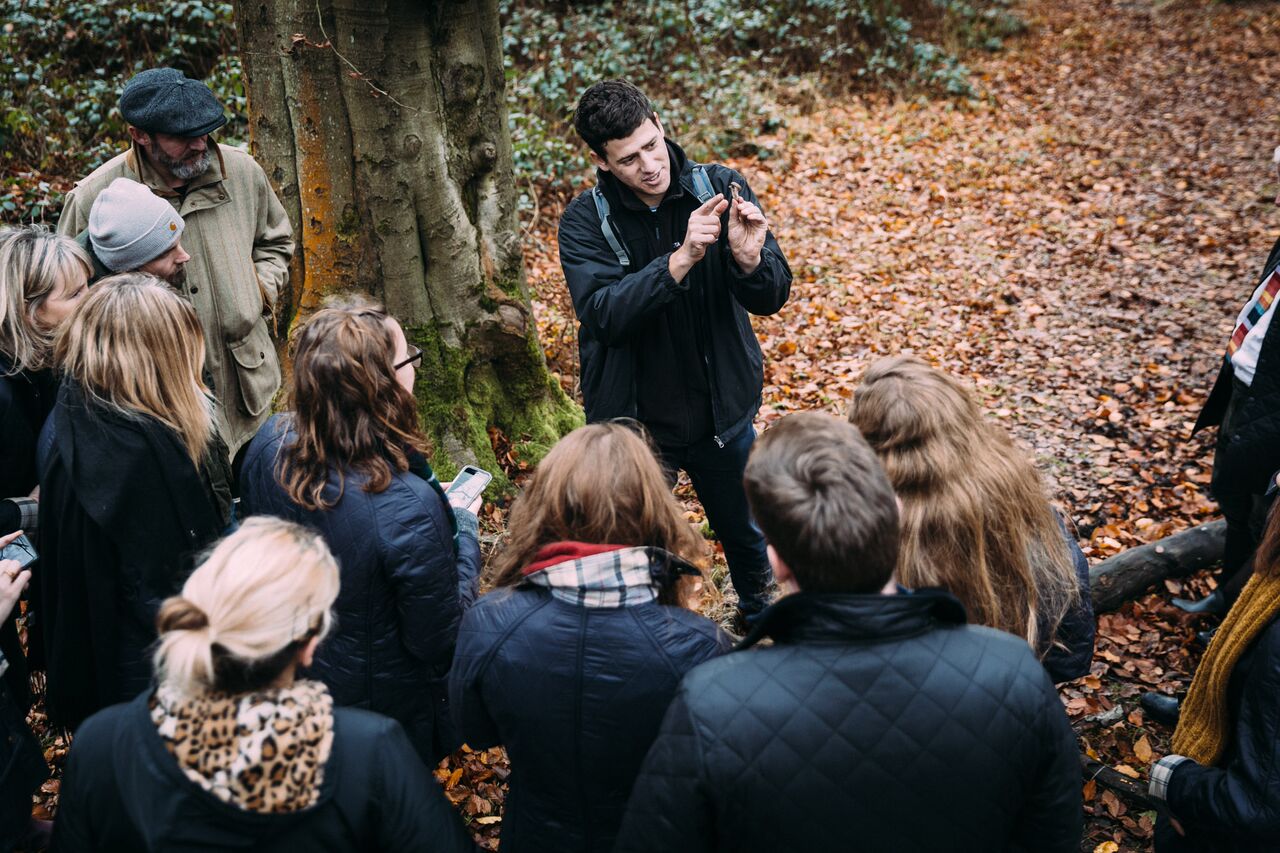 Forager talking to a group of people in woodland surrounding